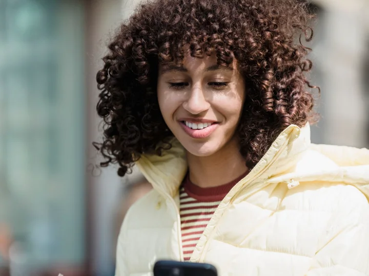 A smiling woman browsing a clinic website on her phone